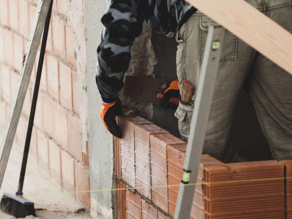 bricklayer-installing-brick-masonry-on-interior-wall- bricklayer-installing-brick-masonry-on-interior-wall-